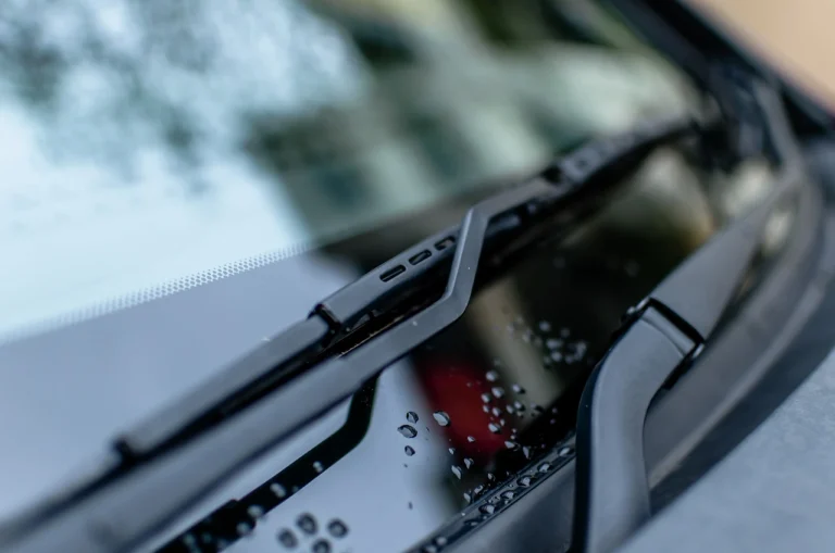 Close-up image of a car windshield wiper blade in action, wiping away rainwater to provide clear visibility. The wiper demonstrates its smooth and efficient performance on a clean, well-maintained windshield.